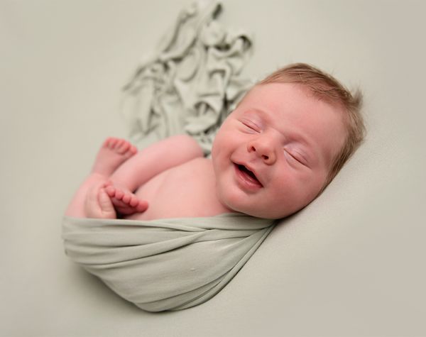 Smiling newborn in sage green photo shoot