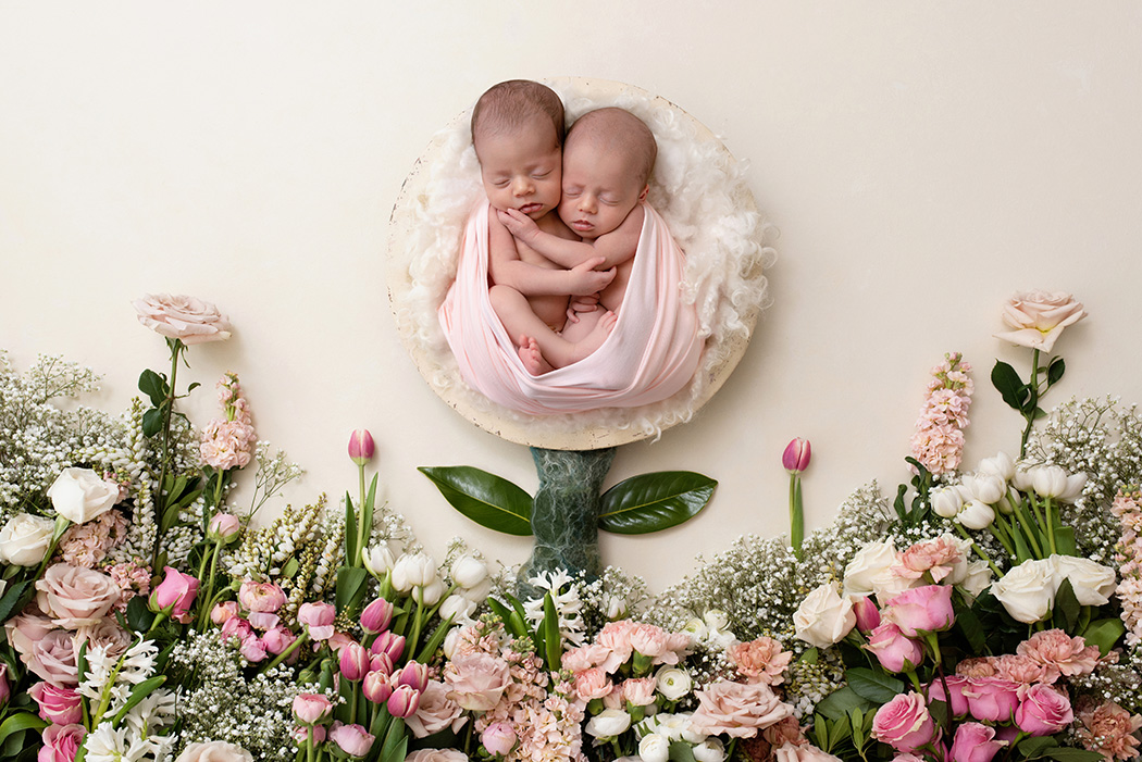 Newborn twin girls surrounded by fresh flowers in digital composite